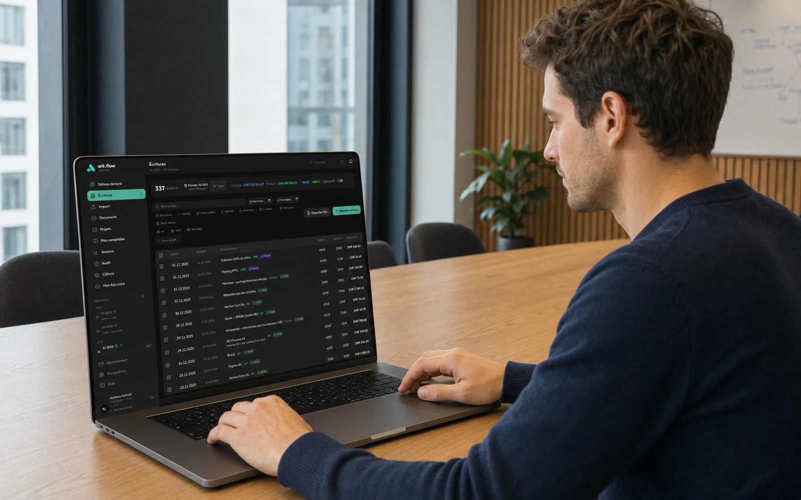 Un entrepreneur travaille naturellement face à son MacBook Pro affichant ark.flow Compta.